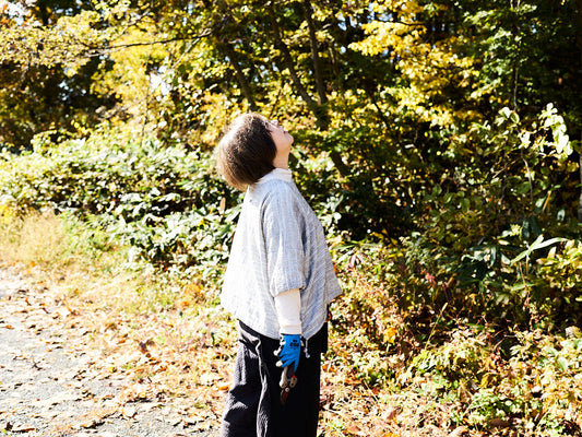Kaoru looking up at trees in autumn forest, holding pruning shears / 秋の森で木を見上げるかおるさん、剪定ばさみを手にしている