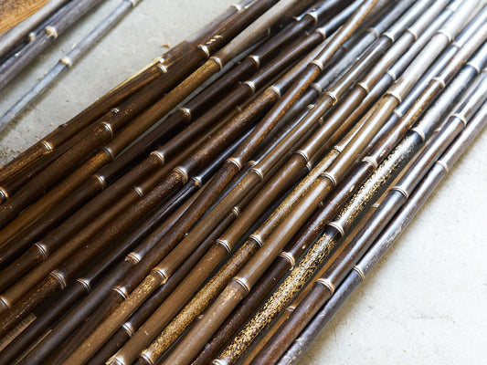 Black bamboo poles with natural variations in color, sheen, spots, and surface markings after processing at Kanasaki Bamboo Materials / 金﨑竹材店で加工を終えた黒竹。一本ごとに異なる色艶や斑点、表面の模様が見られる様子