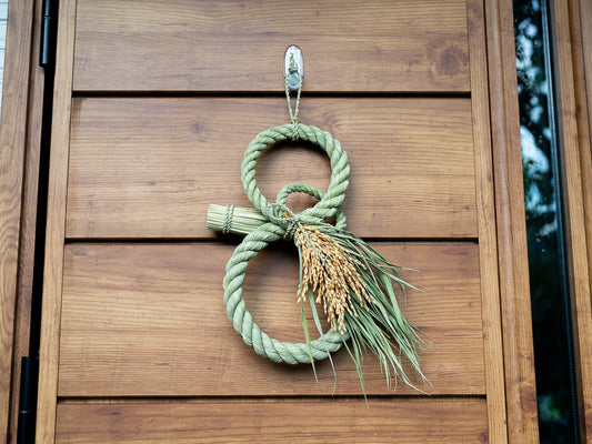 Japanese New Year shimekazari made of straw hanging on wooden door / 木の扉に掛けられた藁製の正月飾り しめかざり