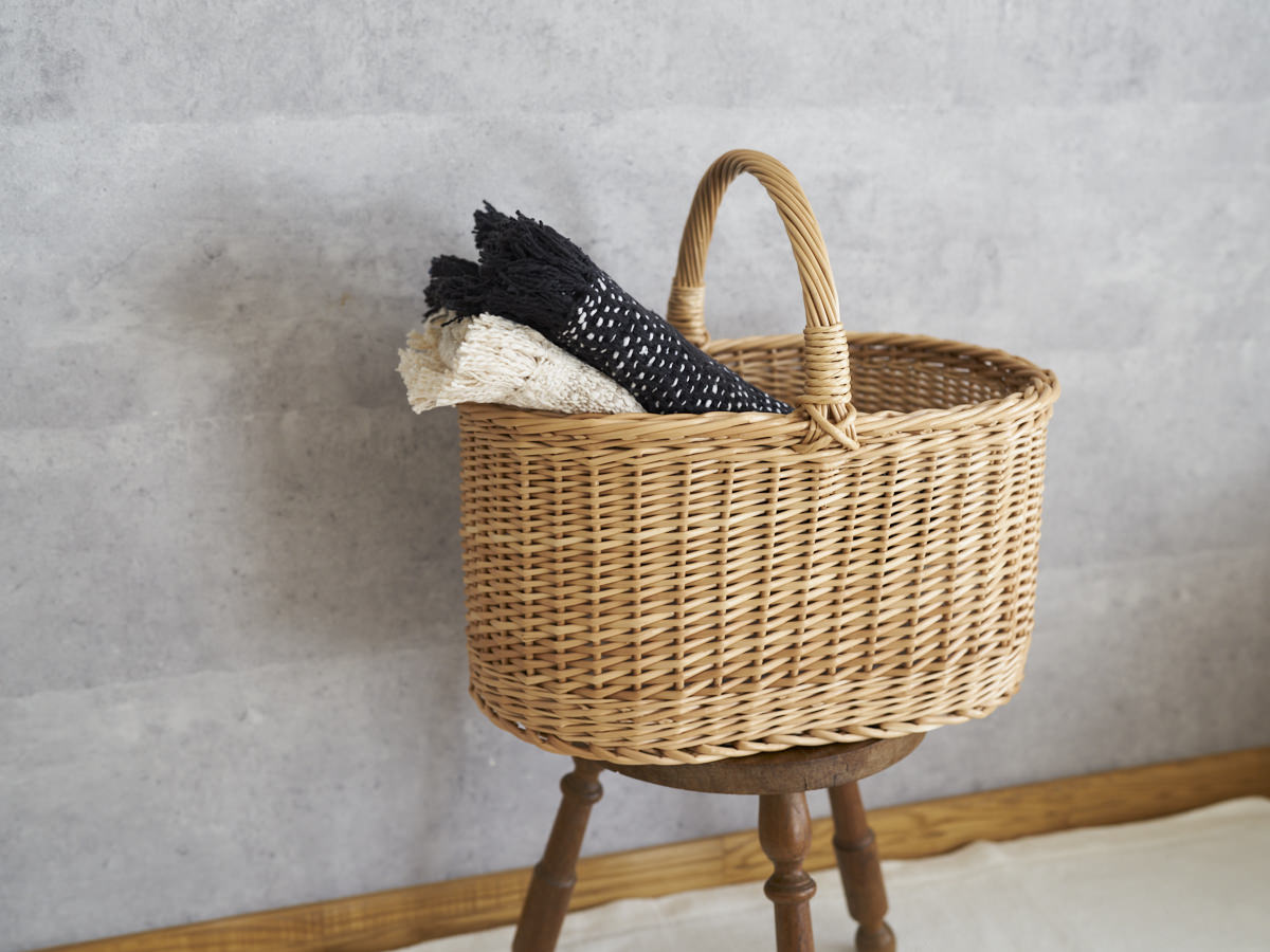 Picnic basket XL with willow weave holding two folded stoles on a stool / リトアニアやなぎのピクニックバスケットXLにストールを入れた様子