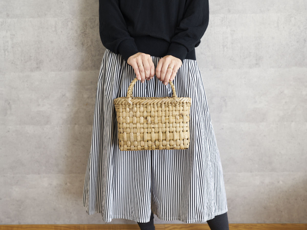 Walnut bark checker handbag with wide light strip held in hand / くるみの総表皮市松編み手提げ（巾広ライン入り）を手に持った様子