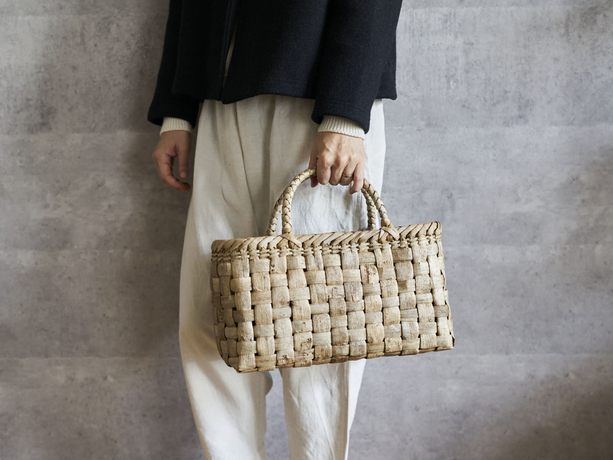 Walnut bark wide checker handbag held in hand / くるみの総表皮市松編みのワイド手提げを手に持った様子