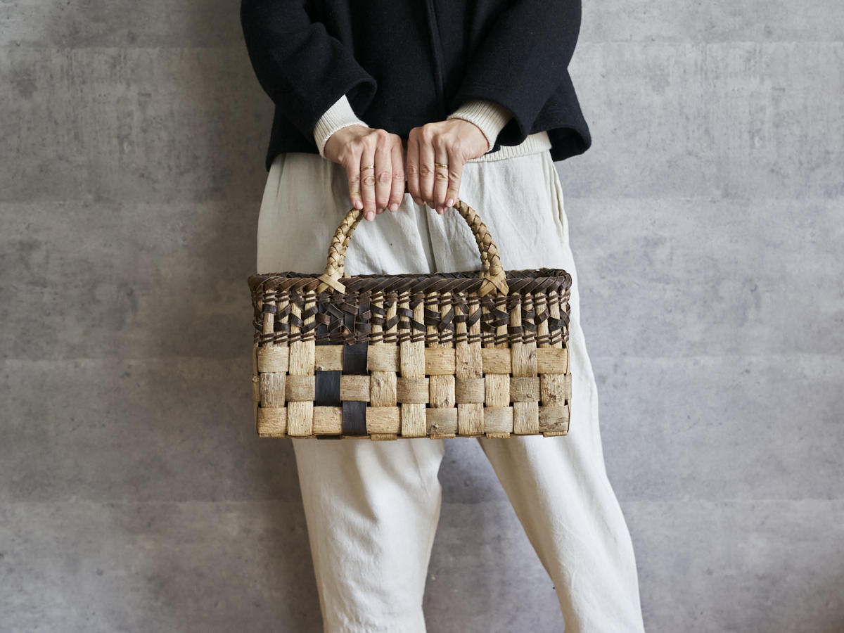 Walnut bark checker handbag with mosaic pattern held in hand / くるみの表皮市松編み手提げ（裏皮モザイク）を手に持った様子