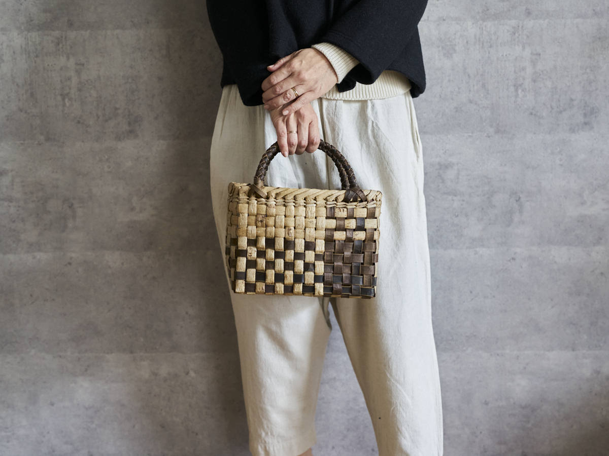Walnut bark checker handbag with puzzle pattern held in hand / くるみの表皮市松編み手提げ（パズル模様）を手に持った様子
