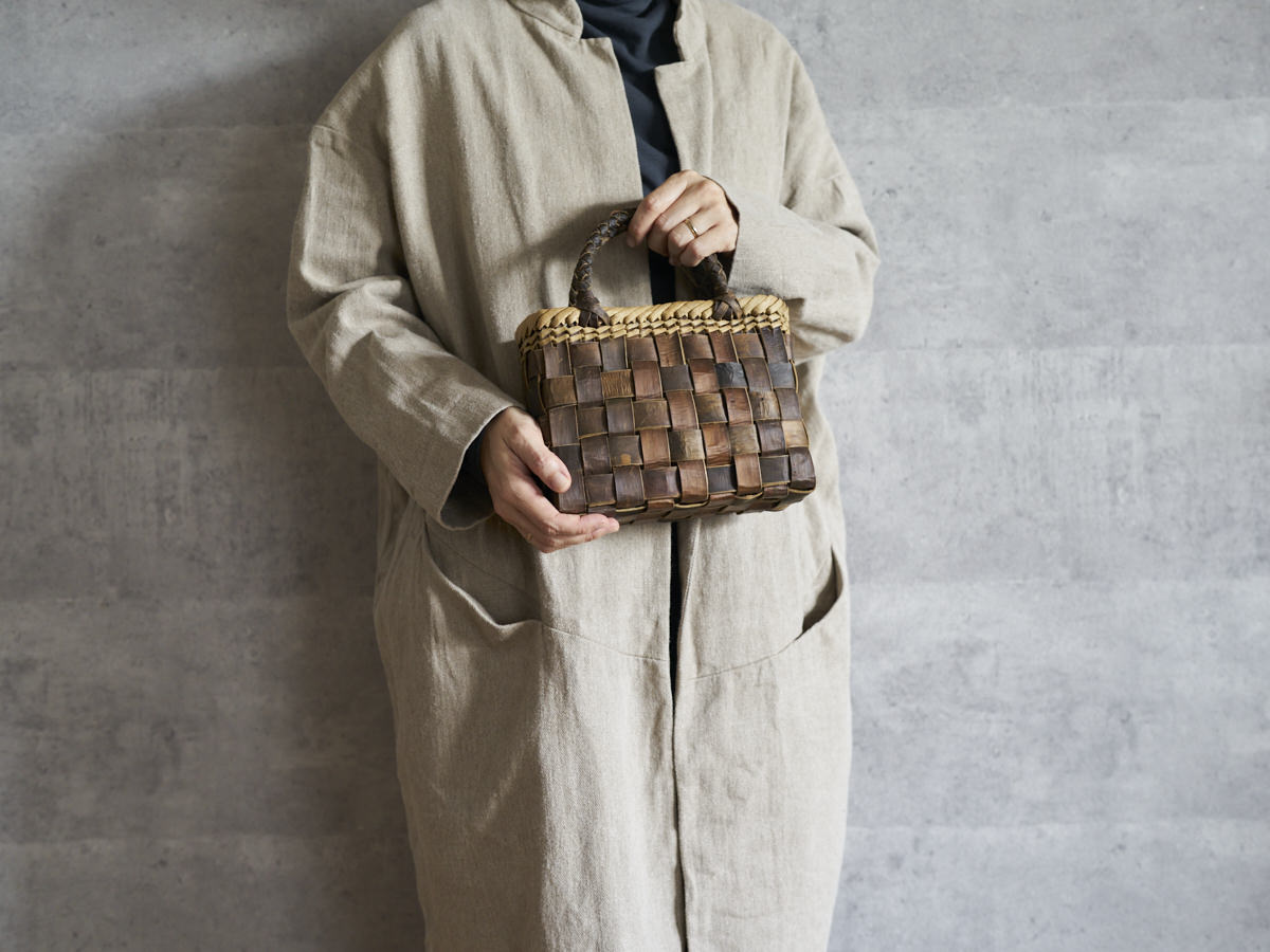 Walnut bark tiny checker handbag held in hand / くるみのtinyサイズ・裏皮市松編み手提げ（縁表皮）を手に持った様子