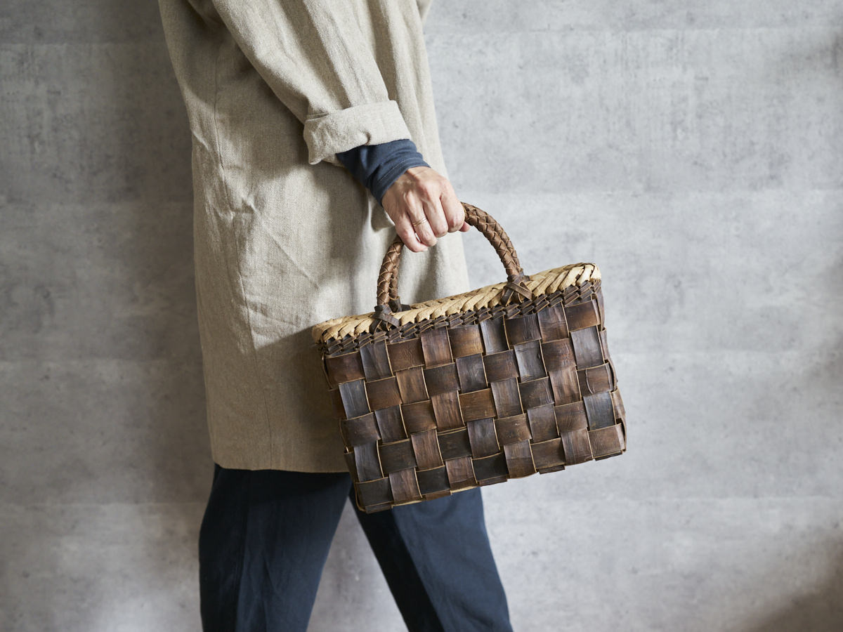 Walnut bark handbag with checker weave held in hand / くるみの裏皮市松編み手提げ（縁表皮）を手に持った様子