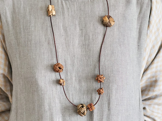 Mixed long pendant made of wild grape vine, walnut, and akebi worn around the neck / 山ぶどう・くるみ・あけびのミックスロングペンダントを首に掛けた様子