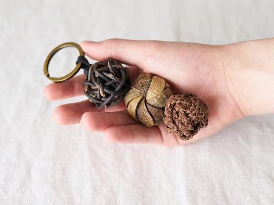 Wild grape vine, walnut, and akebi key holders held in the hand / 山ぶどう・くるみ・あけびのキーホルダーを手に持った様子