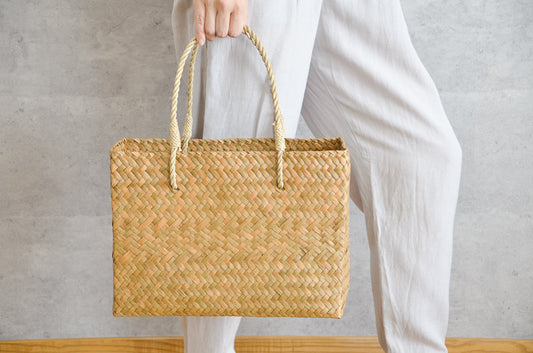 Hand holding a Krajood grass attaché-style basket bag / カチューのアタッシュ型かごバッグを手に持った様子