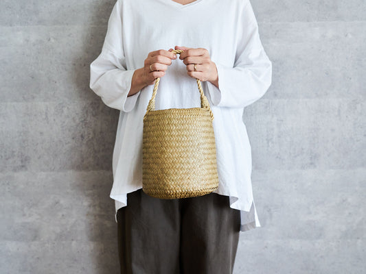 Double-woven one-handle basket bag made of krajood grass being held / カチューの二重編み一本手かごバッグを持っている様子