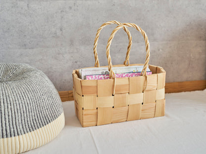 A pine side basket with handles holding magazines placed on the floor / 雑誌を入れたパインの持ち手付きサイドバスケットを床に置いた様子
