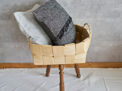 Round pine basket with double handles placed on a stool holding cushions / スツールの上に置いたパインの丸バスケットにクッションを入れた様子