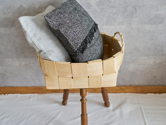 Round pine basket with double handles placed on a stool holding cushions / スツールの上に置いたパインの丸バスケットにクッションを入れた様子