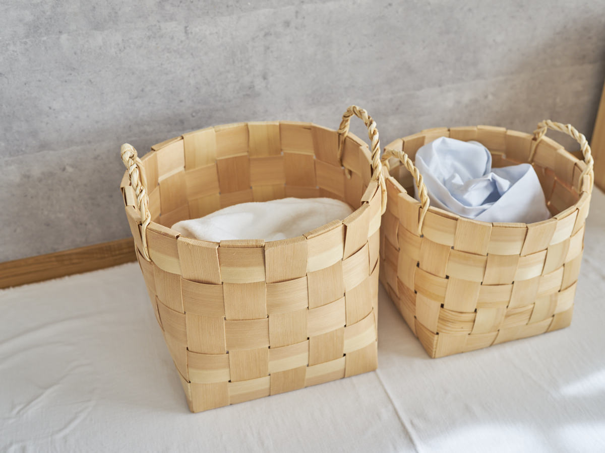 Tall pine laundry baskets with handles holding folded laundry placed side by side / 洗濯物を入れたパインのトール型ランドリーバスケットを並べた様子