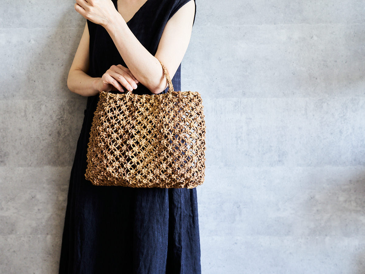 Macrame-style tote basket made of linden bark being held / シナノキの花結び手提げを持っている様子