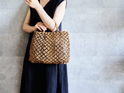 Macrame-style tote basket made of linden bark being held / シナノキの花結び手提げを持っている様子