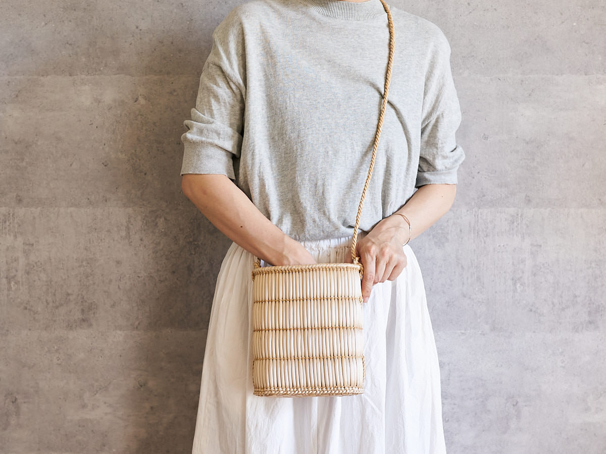 A person wearing a cattail sacoche crossbody at the front of the body / がまのサコッシュを斜め掛けして体の前に下げた様子