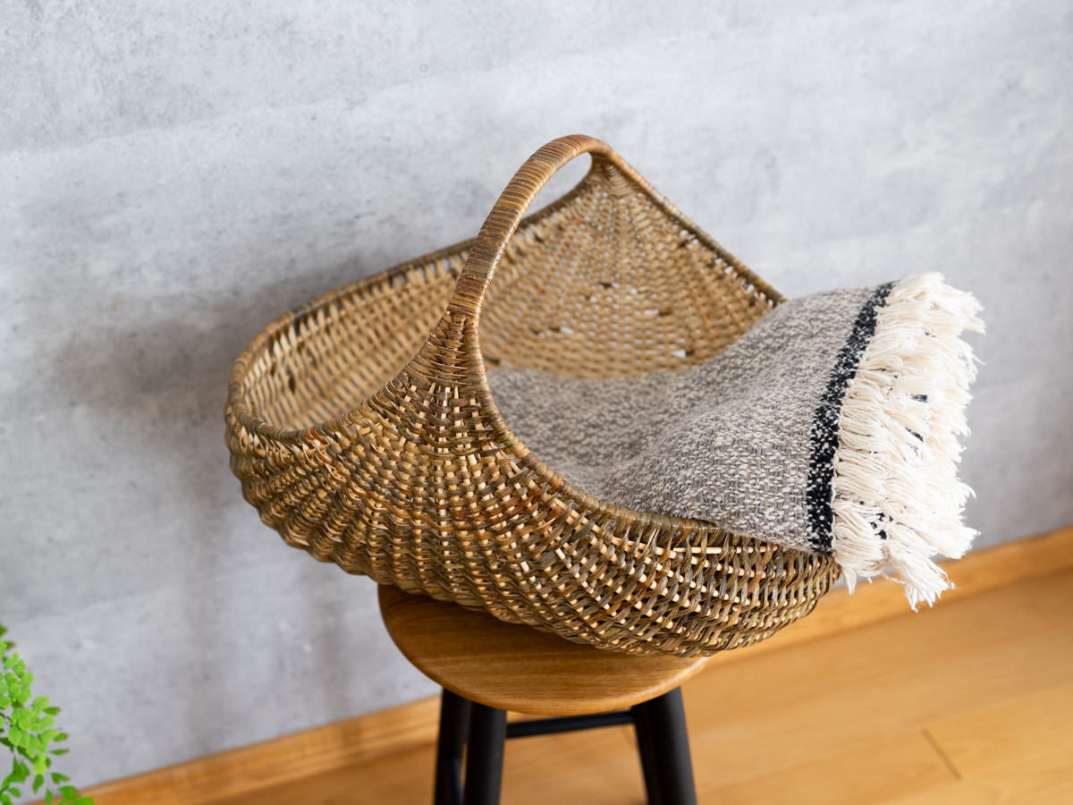 Willow and hazel shopping basket on a stool with a woven throw / やなぎとヘーゼルのショッピングバスケットをスツールに置き、織り布を掛けた様子
