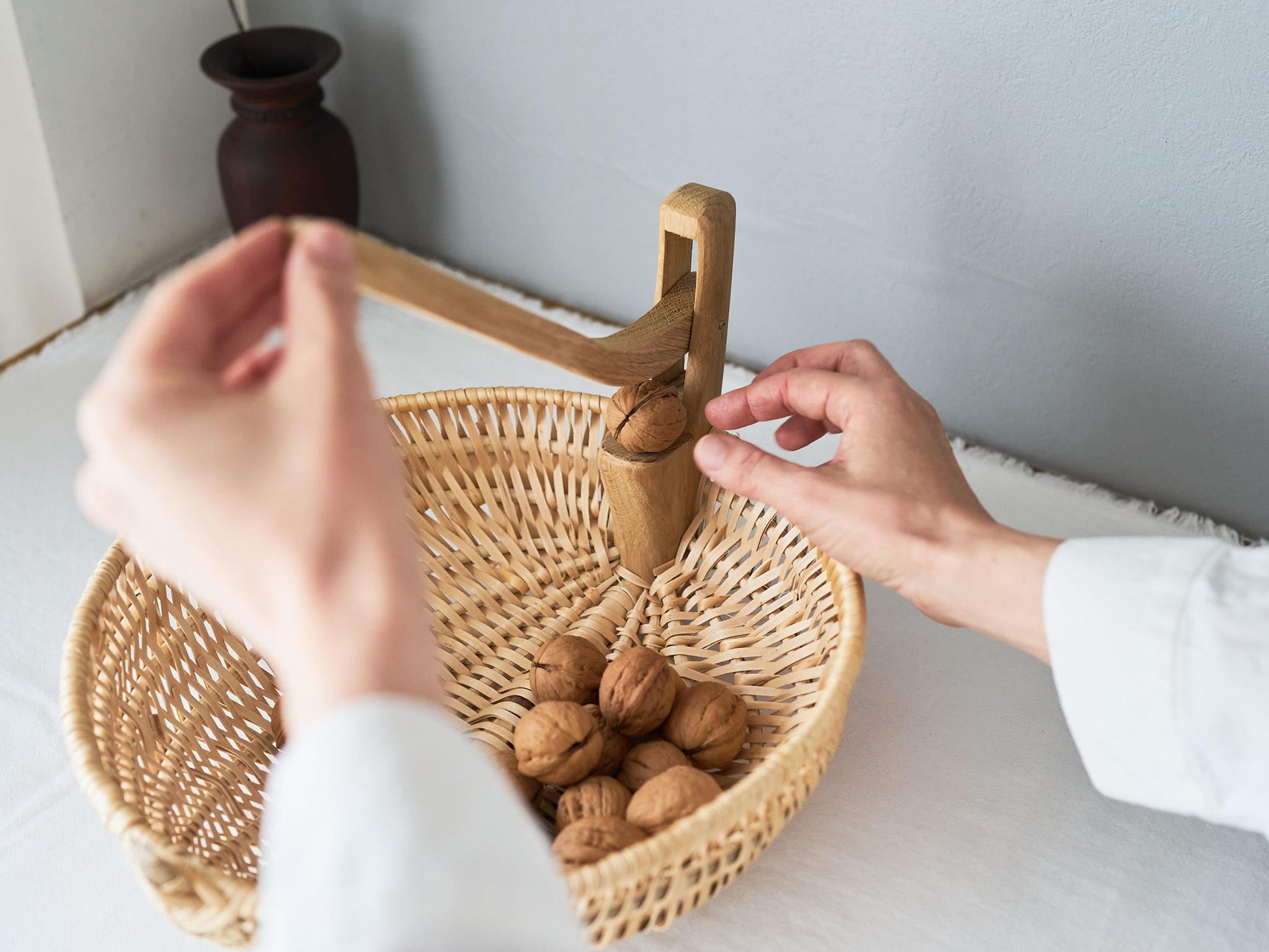 Cracking walnuts with a nutcracker over a basket / かごの上でくるみをくるみ割りで割っている様子