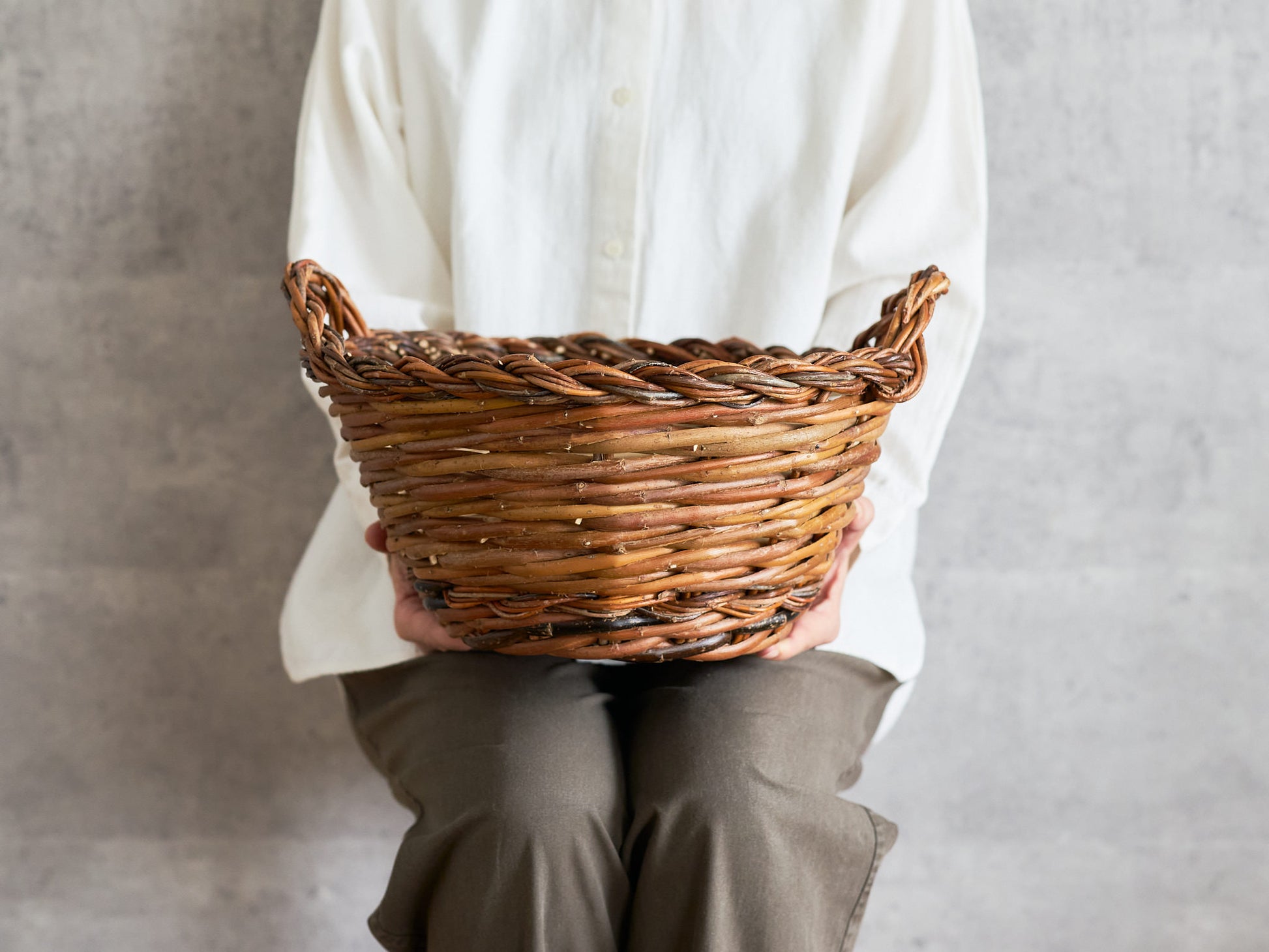 Round willow basket with two handles, handwoven texture visible / 両手つきのやなぎの丸かご、編み目が見える様子