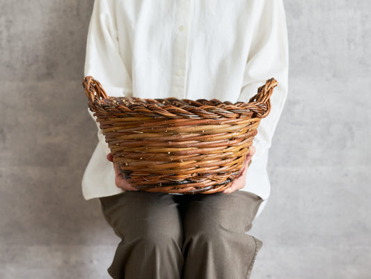 Round willow basket with two handles, handwoven texture visible / 両手つきのやなぎの丸かご、編み目が見える様子